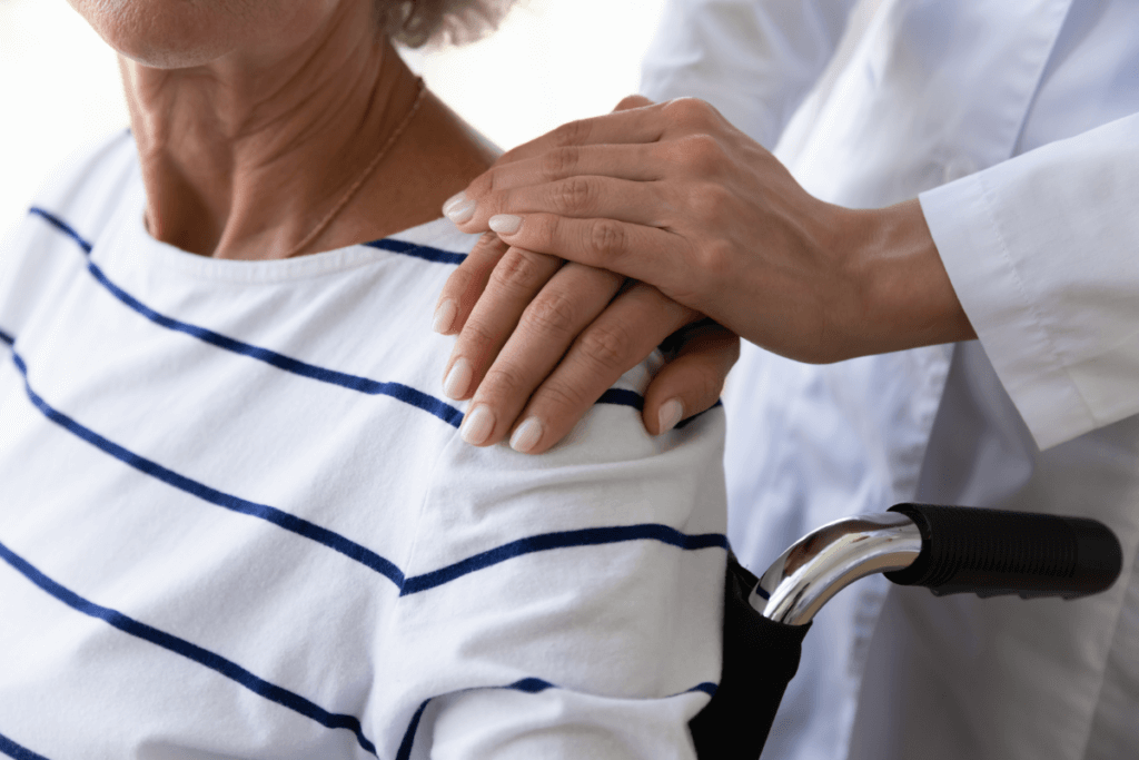 Doctor touching shoulders of patient in a wheelchair. long term disability vs short term.